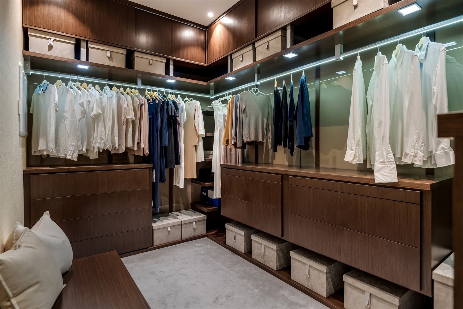 Stor walk-in garderobe med gjennomført design i mørkt tre. En praktisk og elegant løsning med god plass til både klær, sko og tilbehør. Galleribilde