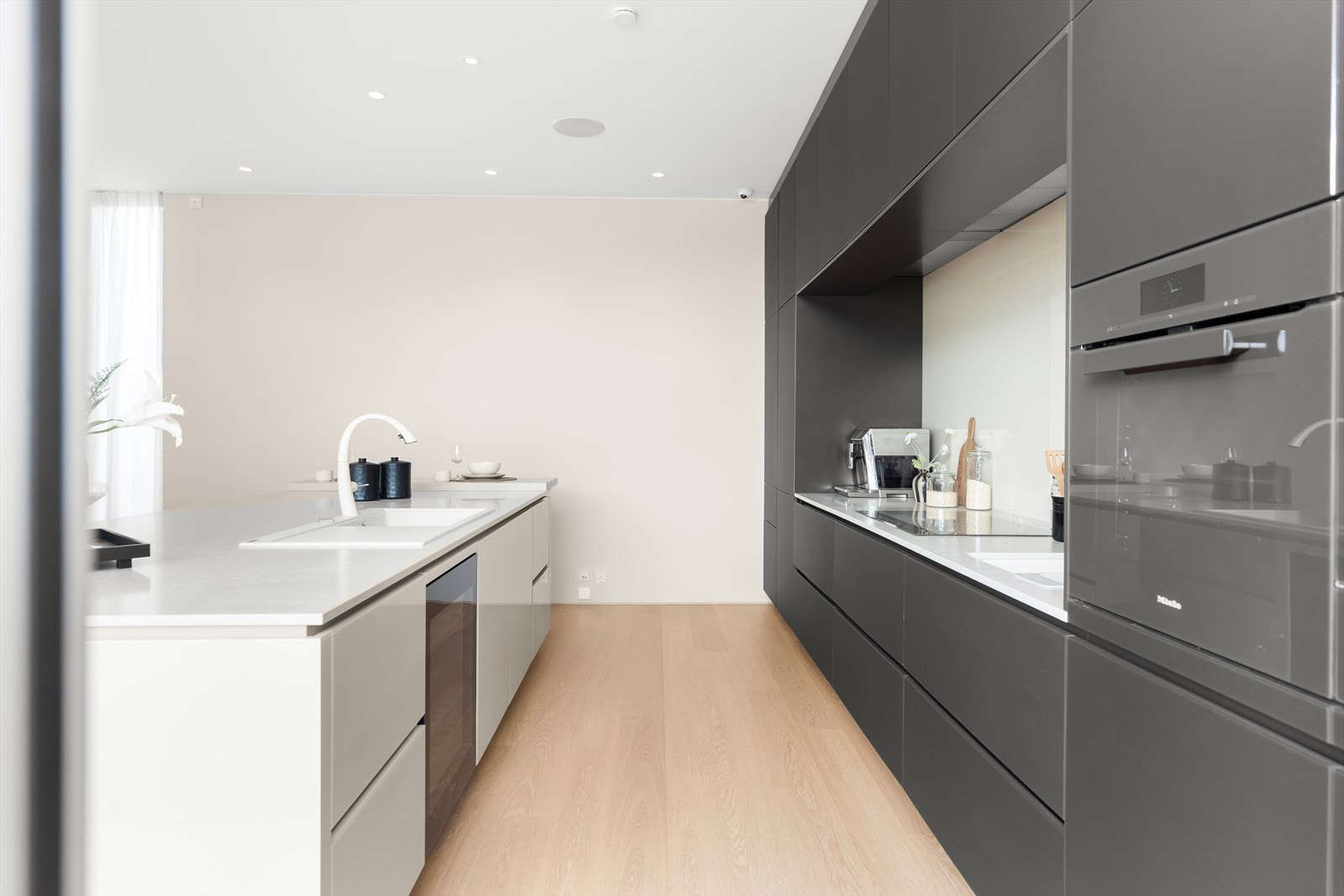 Tidløst kjøkken fra tyske Alno med integrert vinskap, oppvaskmaskin og stekeovn fra Miele, Kueppersbusch induksjonstopp og Liebherr kjøle- og fryseskap. Alt elegant integrert for et helhetlig uttrykk og kompromissløs kvalitet. Galleribilde