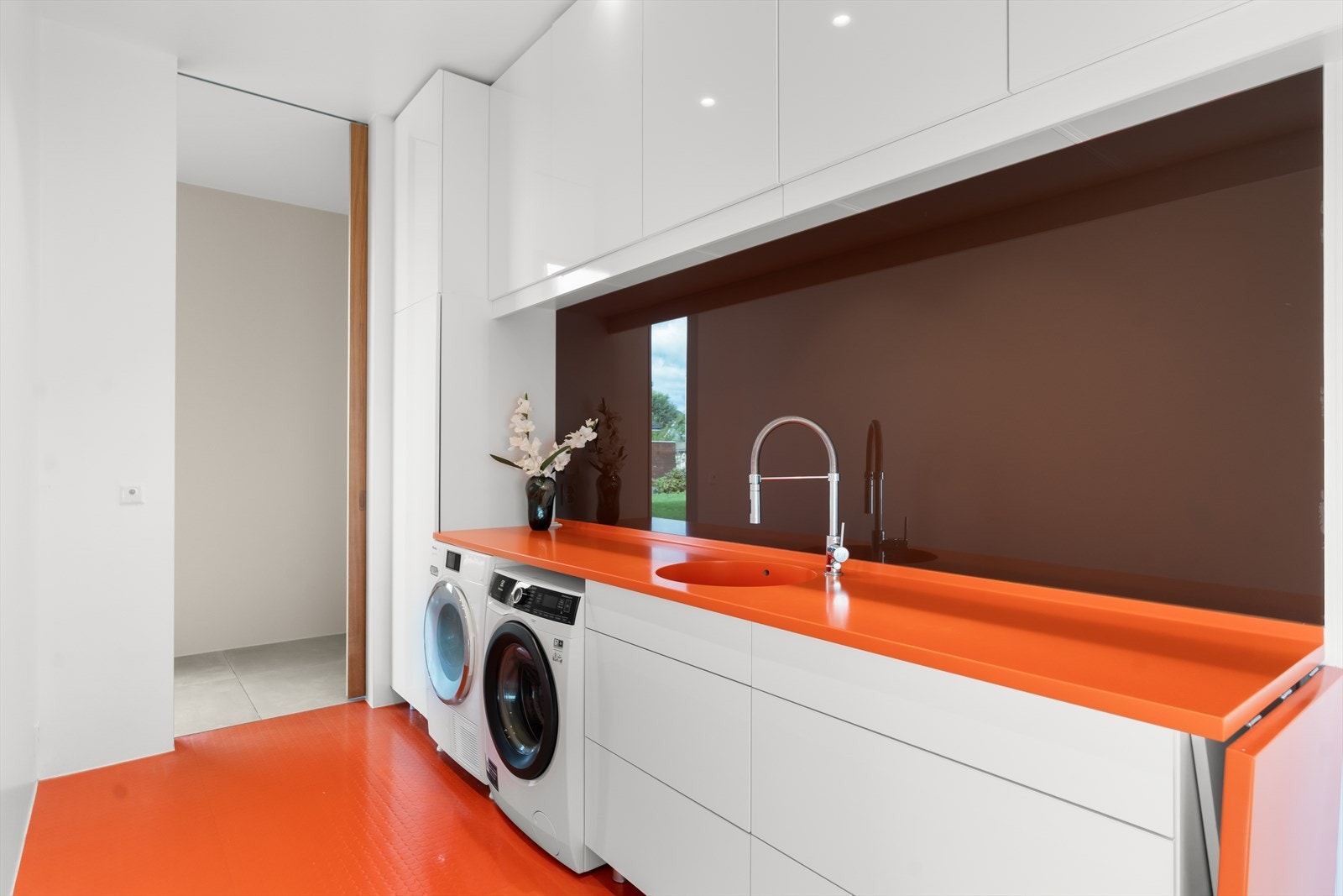 Boligens vaskerom er tidløst med oransje gulv og benkeplate, rikelig med oppbevaringsmuligheter og en praktisk arbeidsflate. Galleribilde