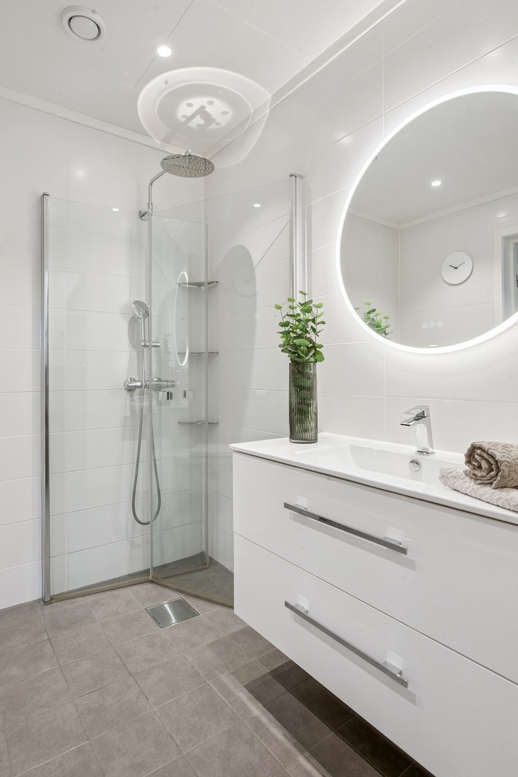 Her er det en romslig dusjnisje med glassdører og en moderne servantinnredning. Galleribilde