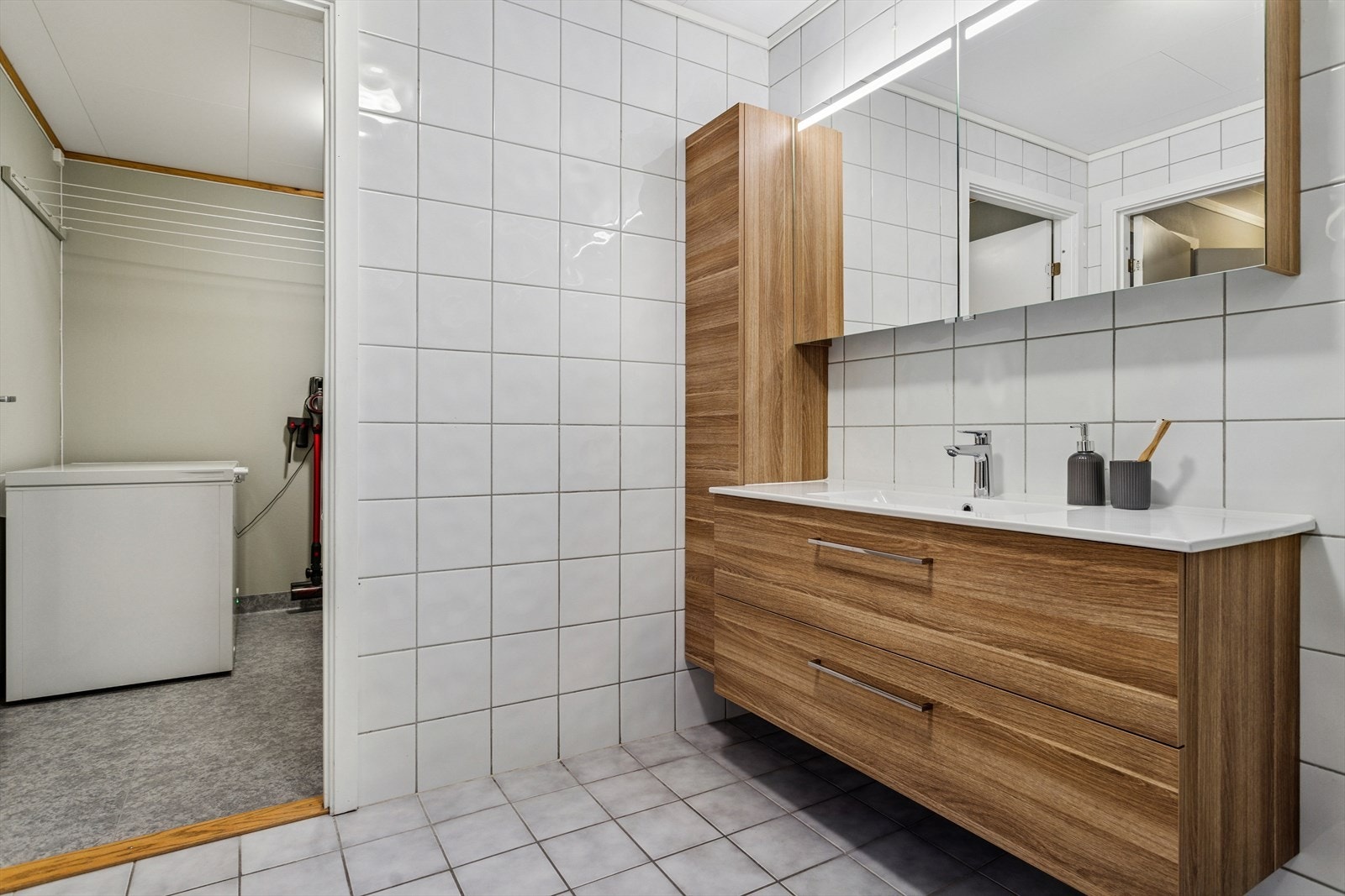 Baderommet er innredet med dusjkabinett, gulvmontert toalett og en stor innredning med mye lagringsplass og heldekkende servant. Galleribilde