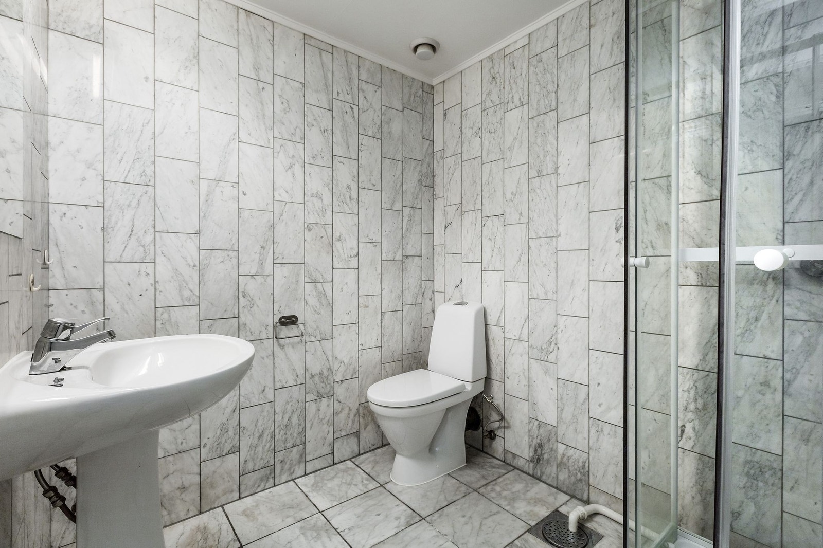 Flislagt baderom innredet servant og speil med overbelysning, samt toalett. Galleribilde