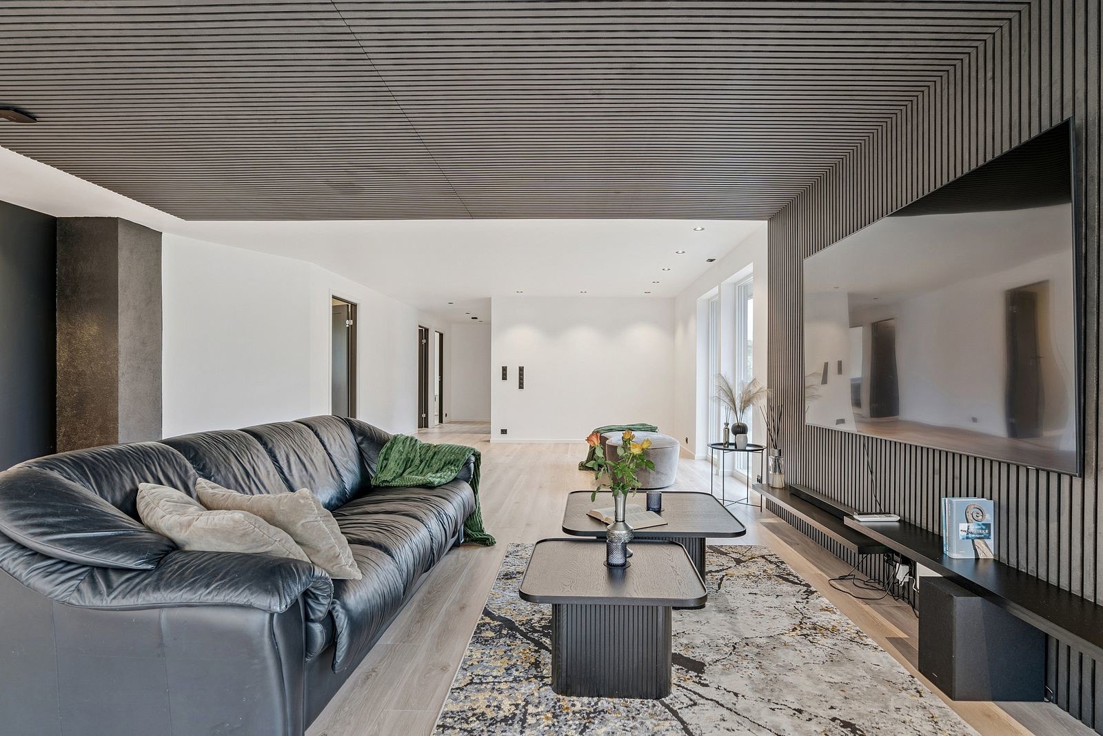 Deler av stuen er avgrenset med stilrene spiler som skaper en lun og innbydende sone for sofagruppe og TV Galleribilde