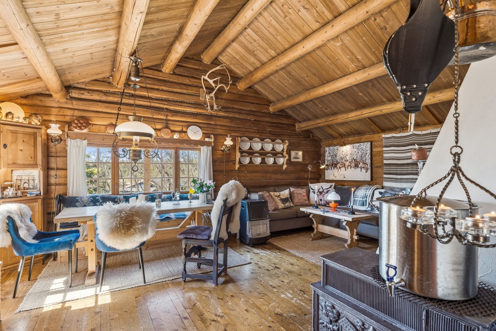 Inne i hytta er det en åpen og romslig stue med rausta himling med syv tømmeråser. Galleribilde