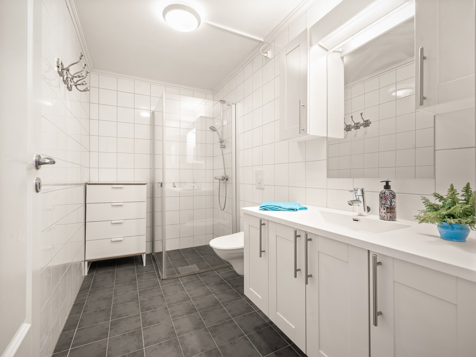 Badet består av servant med innredning, dusjhjørne og vegghengt klosett. Galleribilde