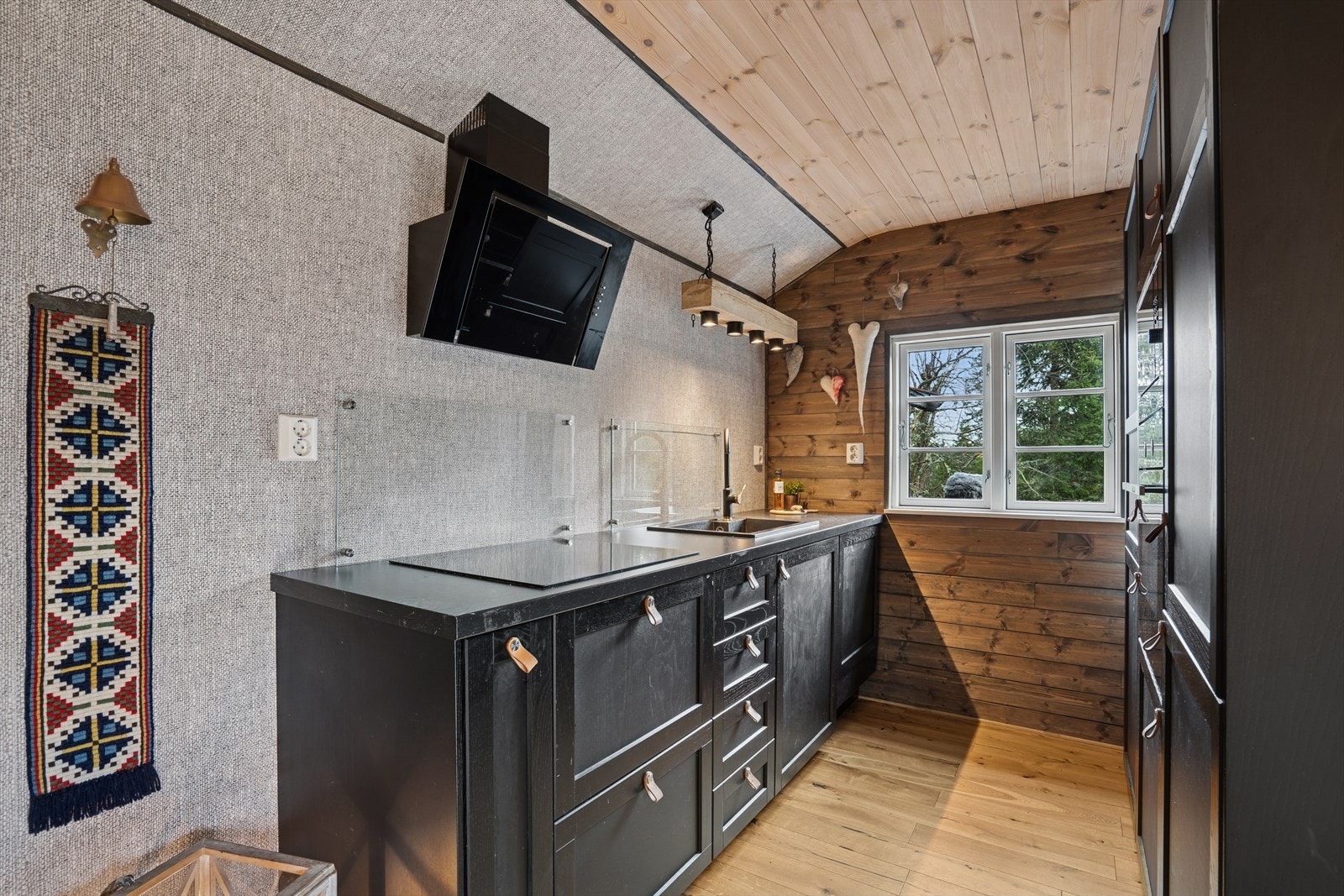 Montert sprutsikre plater bak vask og platetopp. Det er kjøkkenventilator med avtrekk ut. Galleribilde