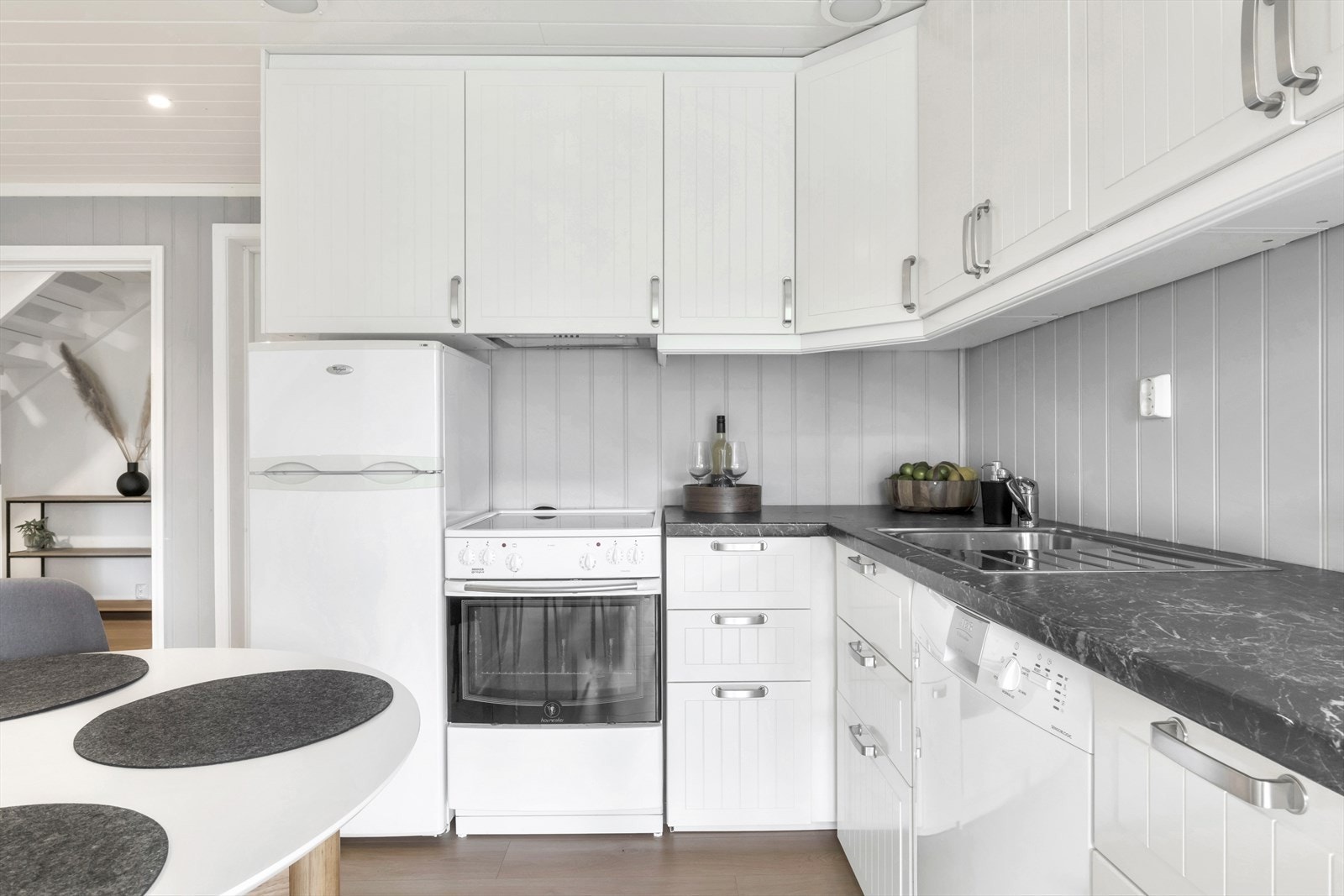 Kjøkkenet i underetasjen har innredning med profilerte fronter, laminat benkeplate, panel over benkeplate, stål oppvaskkum, ventilator og opplegg for oppvaskmaskin Galleribilde