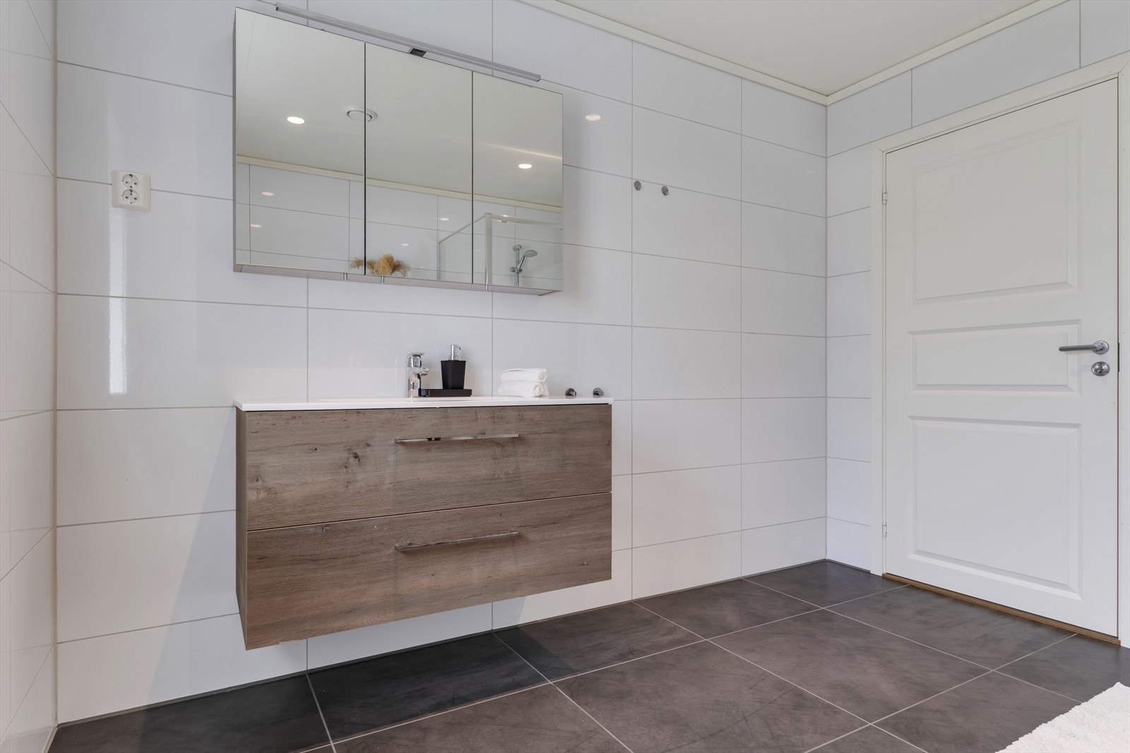 Badet inneholder vegghengt toalett, helstøpt servant og skuffer under med slette fronter Galleribilde