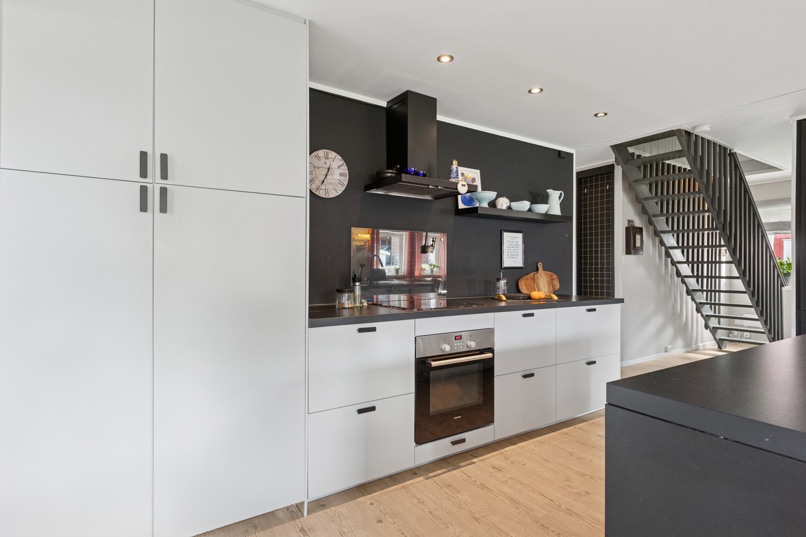Stilrent kjøkken utstyrt med alt av hvitevarer integrert. Vegg og avtrekkshette i dempet sort utførelse. Galleribilde