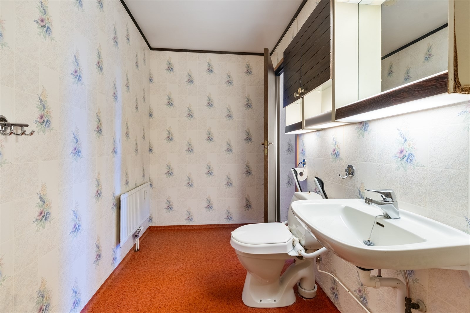 Rommet er innredet med dusjplass, servant, speil med lys og wc. Galleribilde