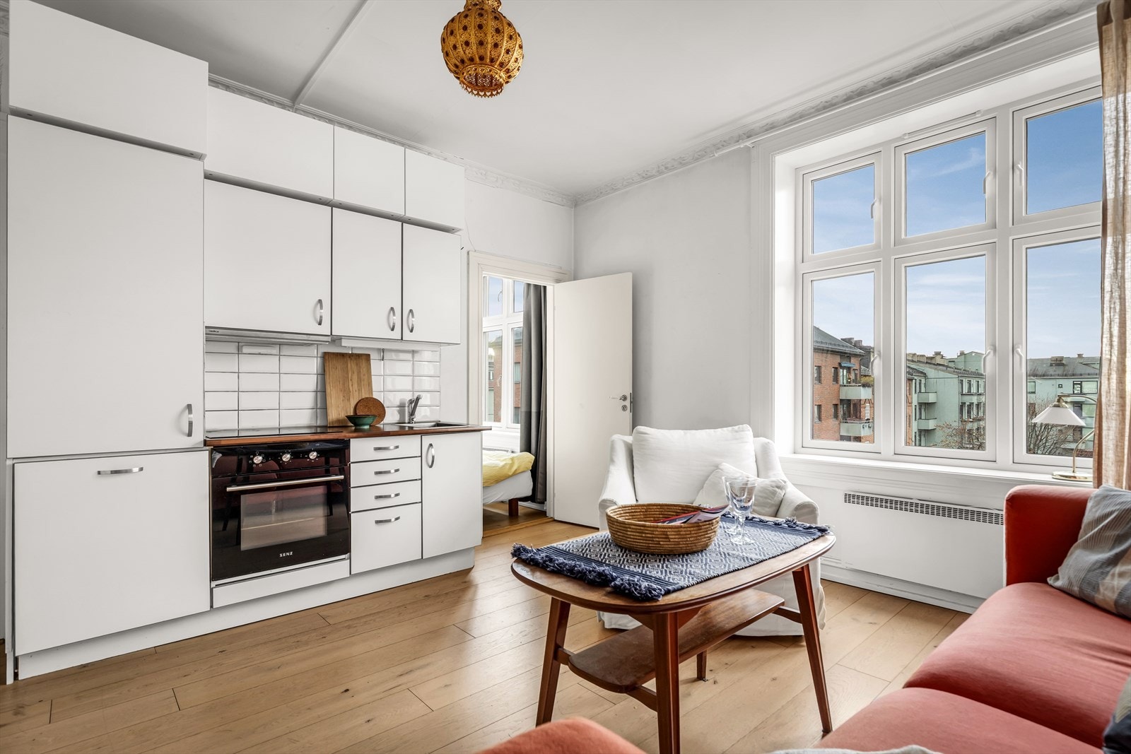 Kjøkkeninnredning med glatte fronter, flislagt vegg under overskap og slitesterk benkeplate. Galleribilde