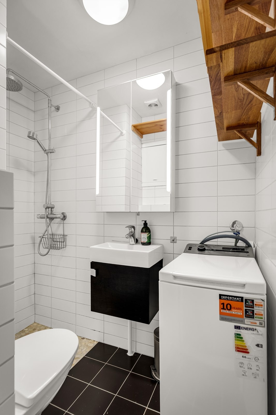 Baderom med innredning bestående av nedfelt vask men benkeskap, overskap med speilfronter og belysning og dusj på gulv. Galleribilde