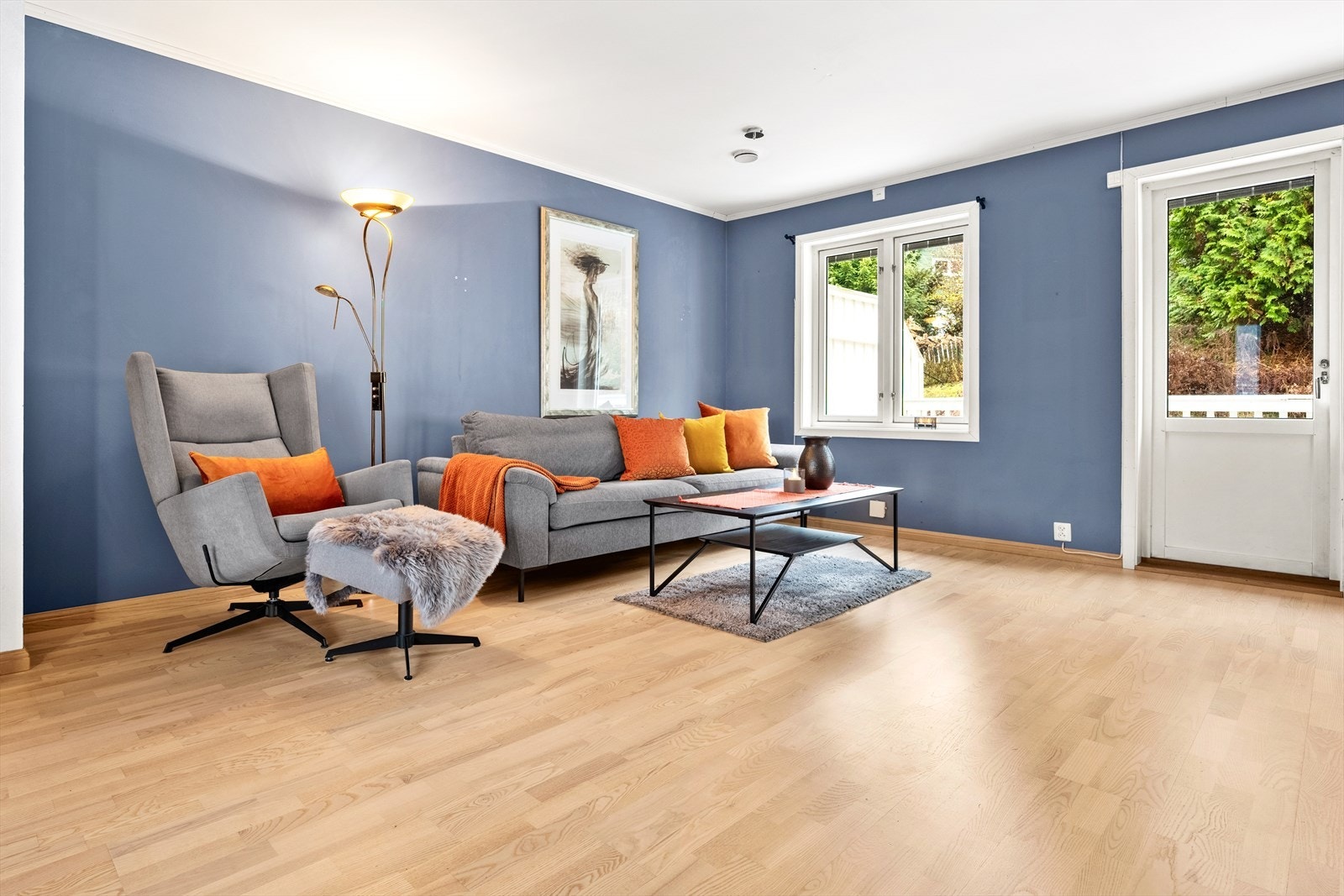 Stuen har pene overflater med parkett på gulv, slette vegger malt i en dempet blåtone. Galleribilde