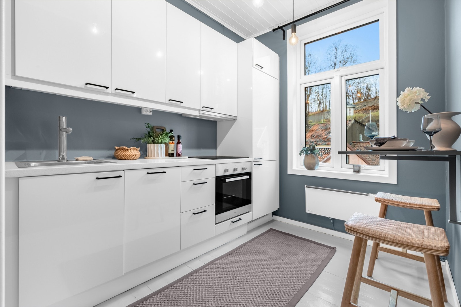 Lys kjøkkeninnredning med hvite, høyglans fronter, og laminat benkeplate Galleribilde