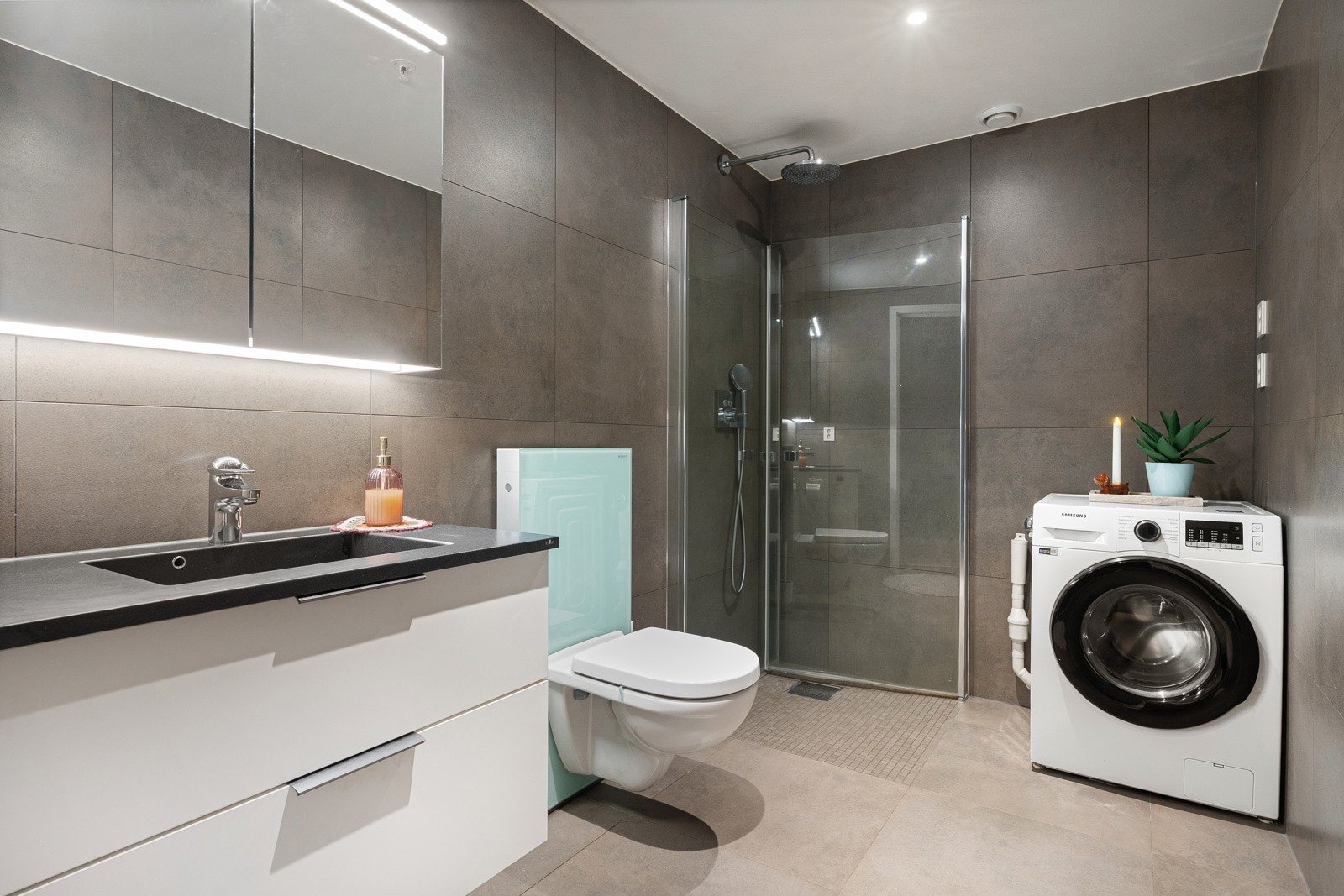 Komplett flislagt bad med innfelt dusjgarnityr som tilvalg og oppgradert toalett. Nedfelt servant og rikelig med lagringsplass i innredningen. Varme i gulv og opplegg for vaskemasking og trommel.