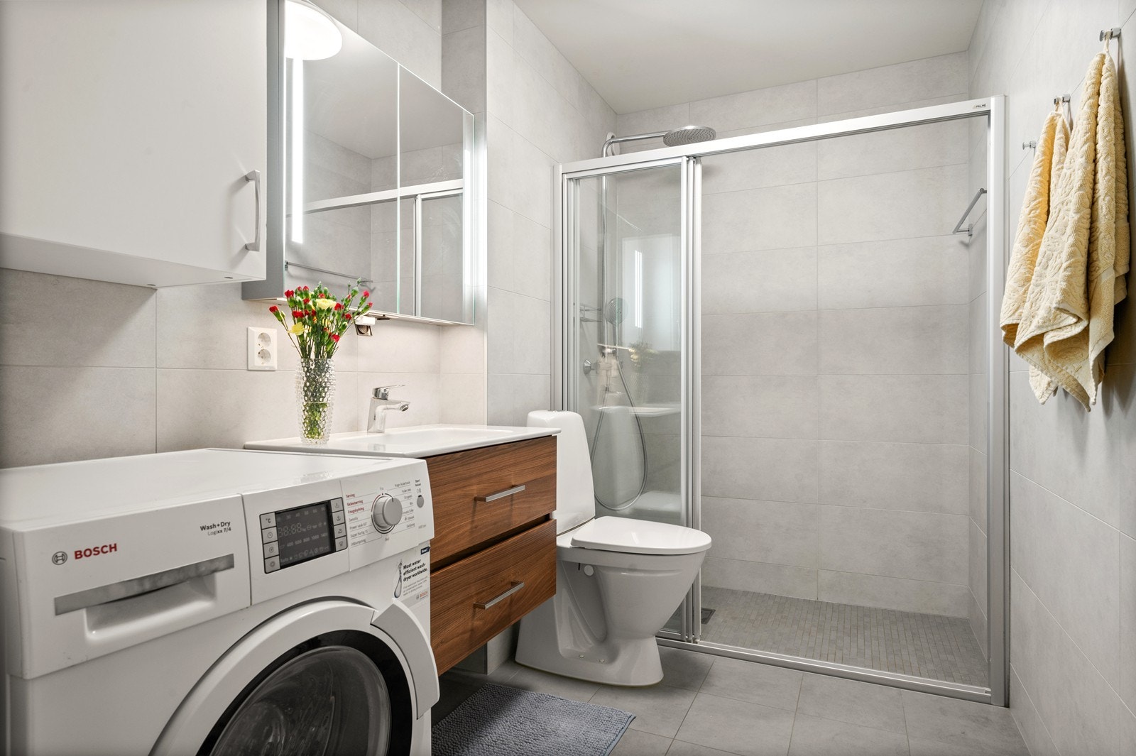 Delikat, flislagt bad med gulvvarme, dusjhjørne og opplegg for vaskemaskin. Galleribilde