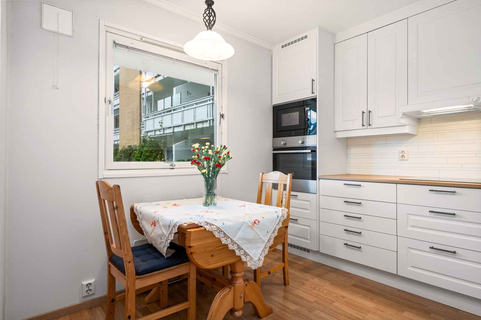 Lyst og funksjonelt kjøkken med spiseplass ved vinduet og integrerte hvitevarer. Galleribilde