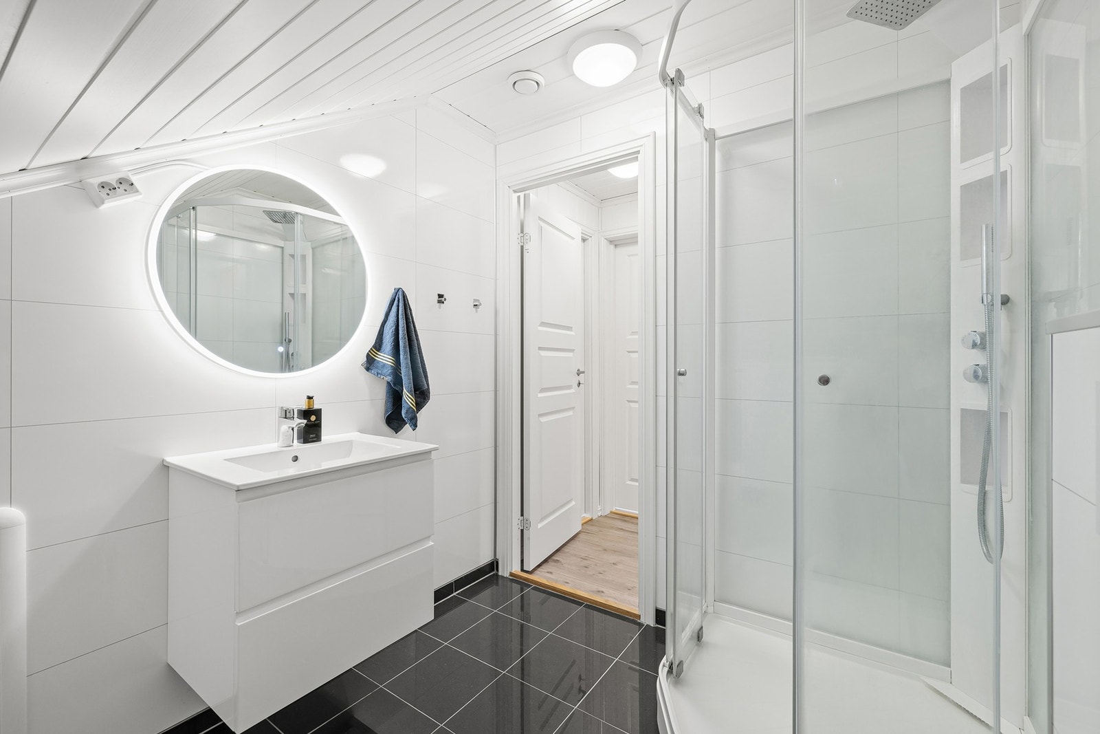 Badet har et dusjkabinett med regnfallsdusj, og det er tilkoblet et vegghengt vannklosett. Galleribilde