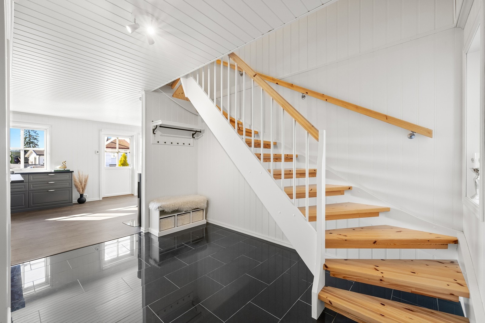 Innenfor døra kommer du til en lys og åpen entré med flislagt gulv med underliggende gulvvarme. Det er plass til yttertøyet, med mulighet for knagger, skohylle og speil. Galleribilde