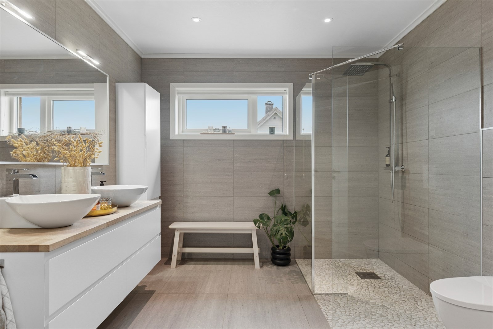 Lekkert baderom fra byggeår, innredet med dusjhjørne, vegghengt toalett og dobbelservant med innredning, speil og belysning. Helfliset og moderne! Galleribilde