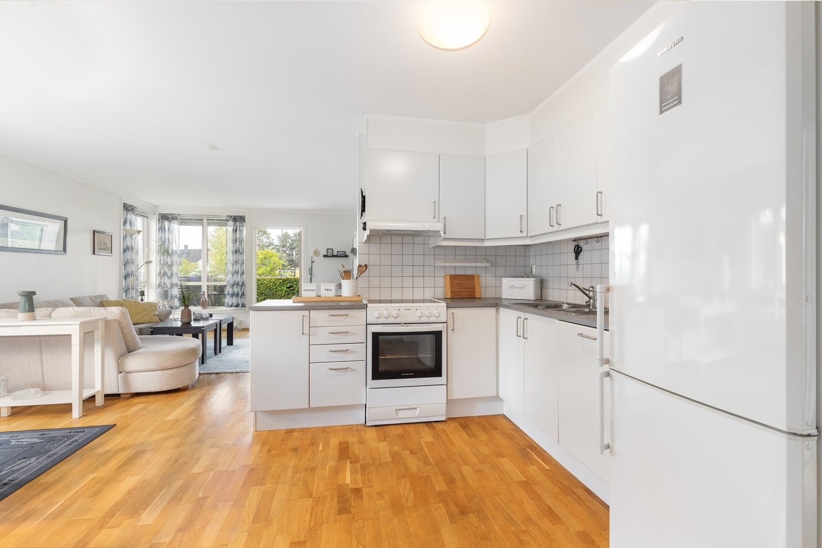 Kjøkkeninnredningen er tidløs med slette hvite fronter på skaper og skuffer med takhøye overskap og benkeplatene er av laminat. Galleribilde