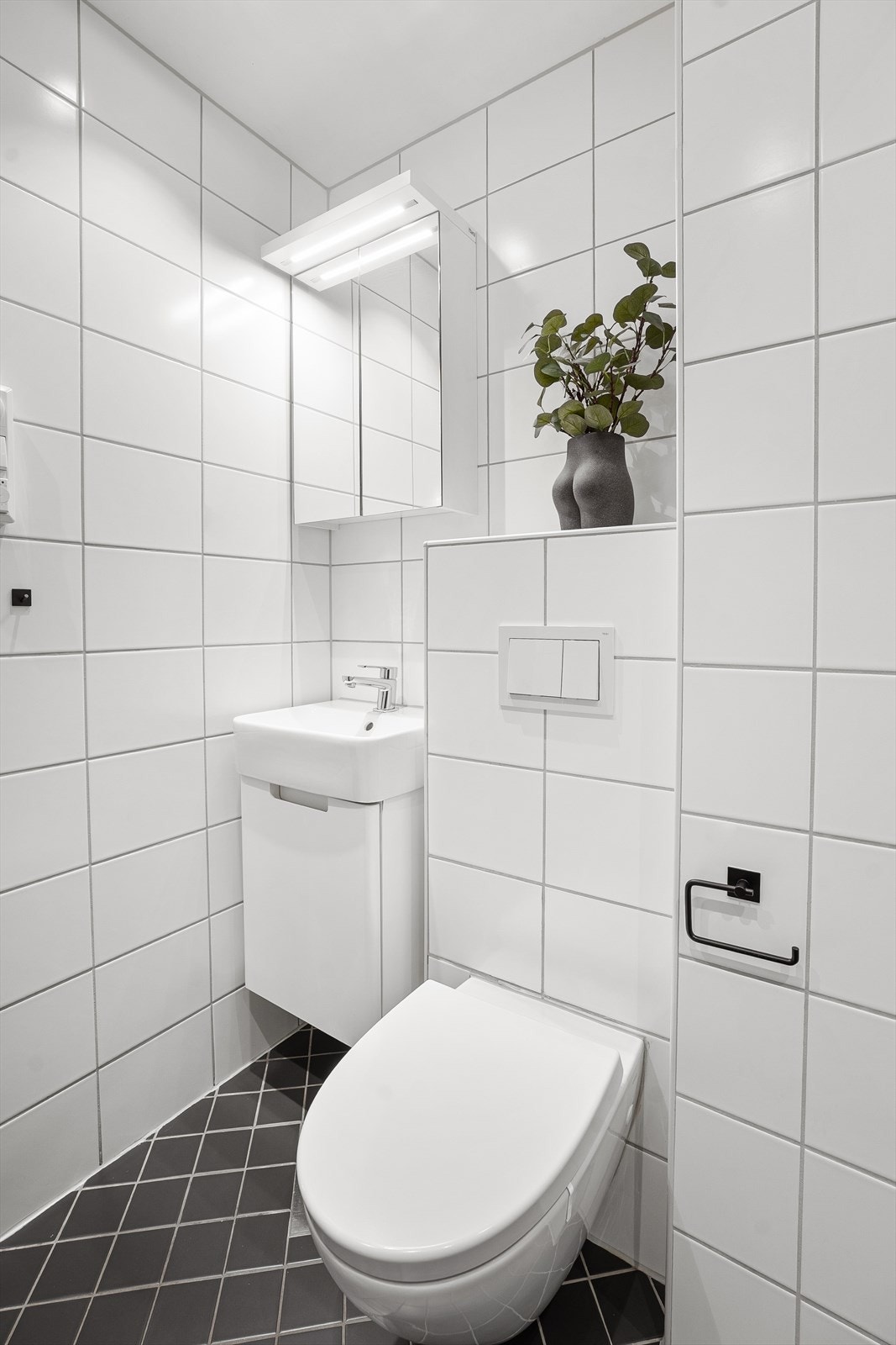 Badet er utstyrt med vegghengt servantskap, ovenpåliggende servant med ett-greps armatur, vegghengt toalett, speilskap med belysning og stikkontakt på vegg over servant. Galleribilde