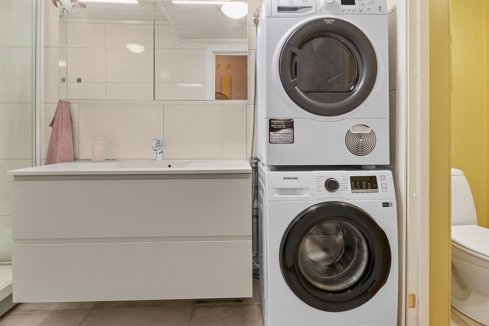 Servant med bred benk og store skuffer, speil overskap og dusjkabinett. Badet har naturlig ventilering. Dør inn til toalettrom er fjernet. Galleribilde