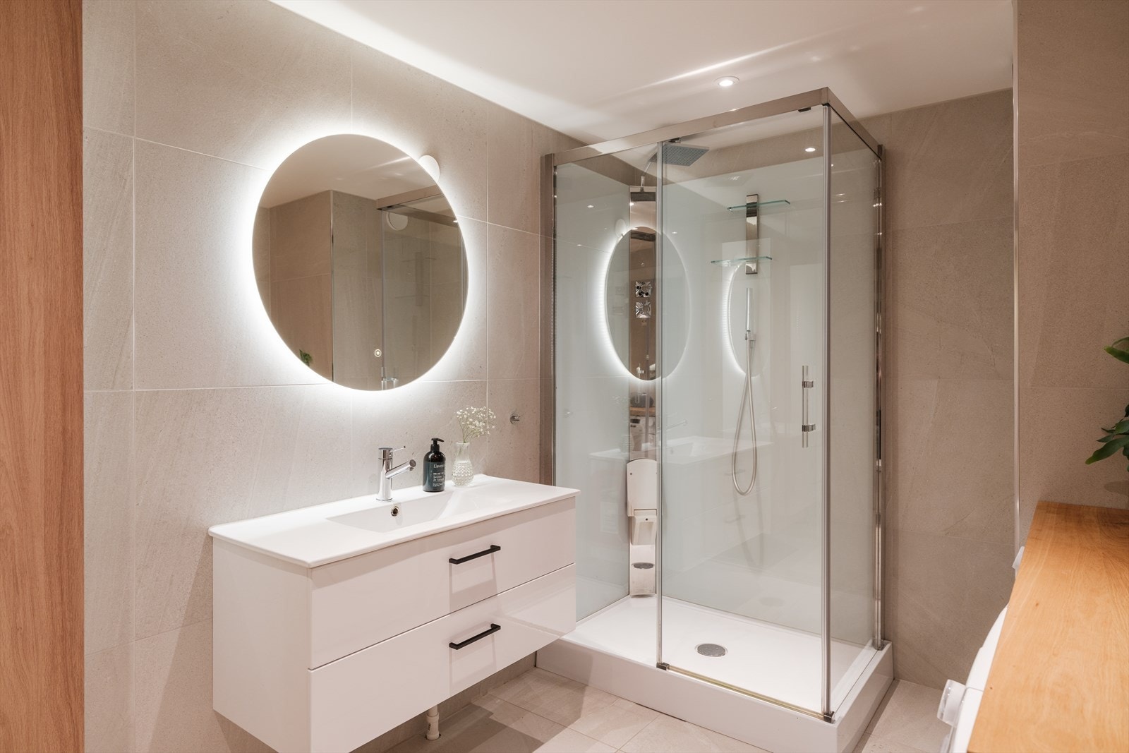 Innredningen er hvit med glatte skuffefronter, heldekkende servant og speil med integrert belysning. I tillegg er det et høyskap med trefargede fronter. Galleribilde