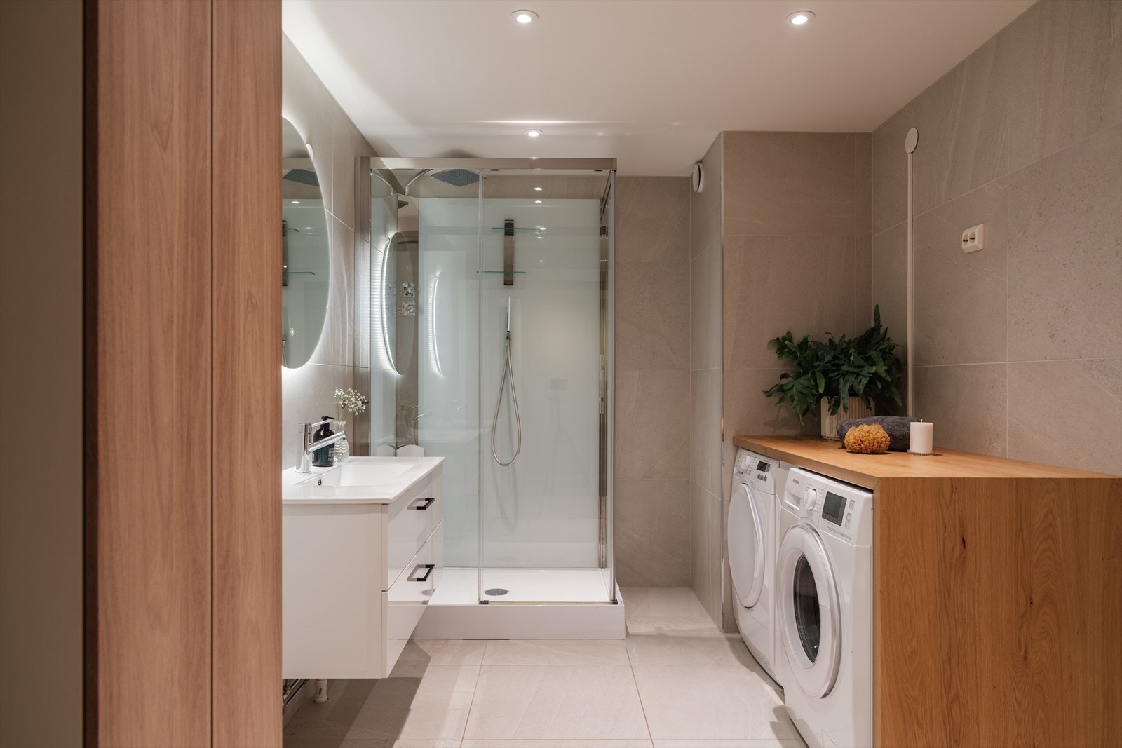 Badet er stort og delikat med romslig dusjkabinett, veggmontert toalett, samt plass til vaskemaskin og tørketrommel under spesialtilpasset benkeplate. Galleribilde