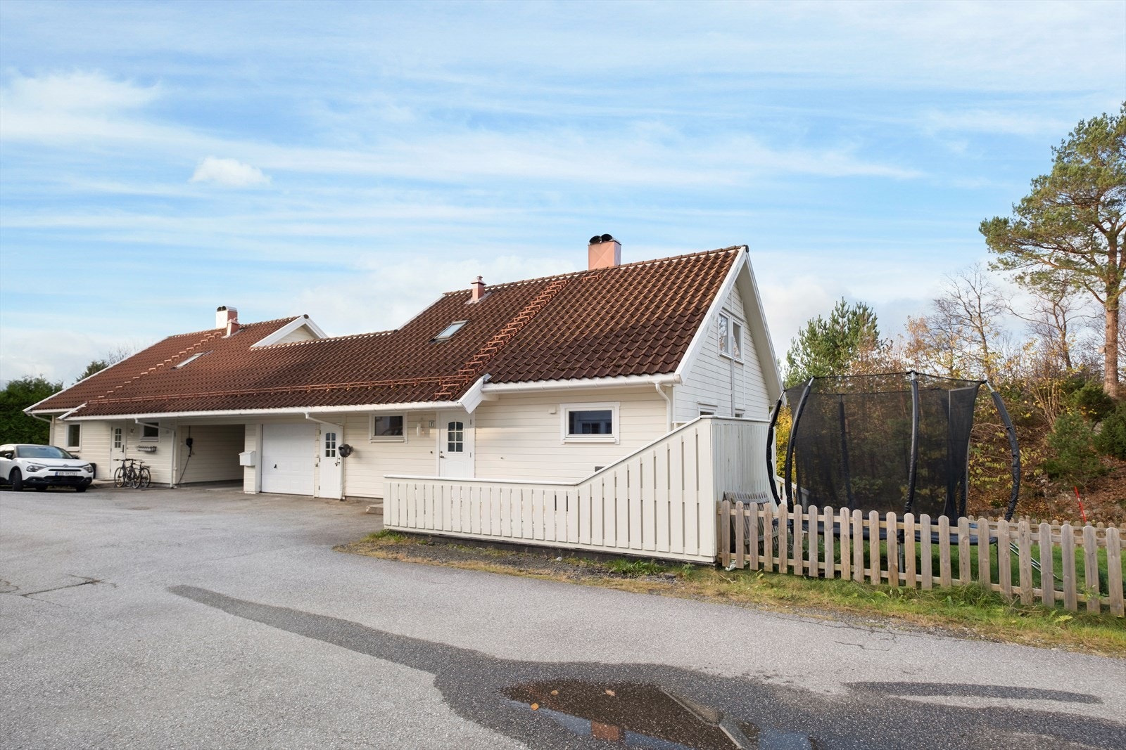 Boligen har en støttemur opp mot hage og plen, og ligger i en vesthelling Galleribilde