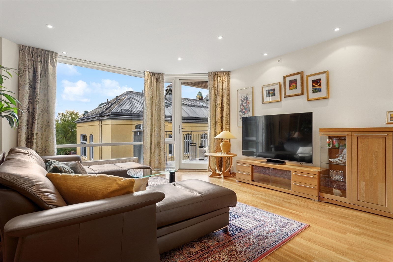 Stue med store vindusflater gir lys og utsikt til nærliggende bygninger. Galleribilde