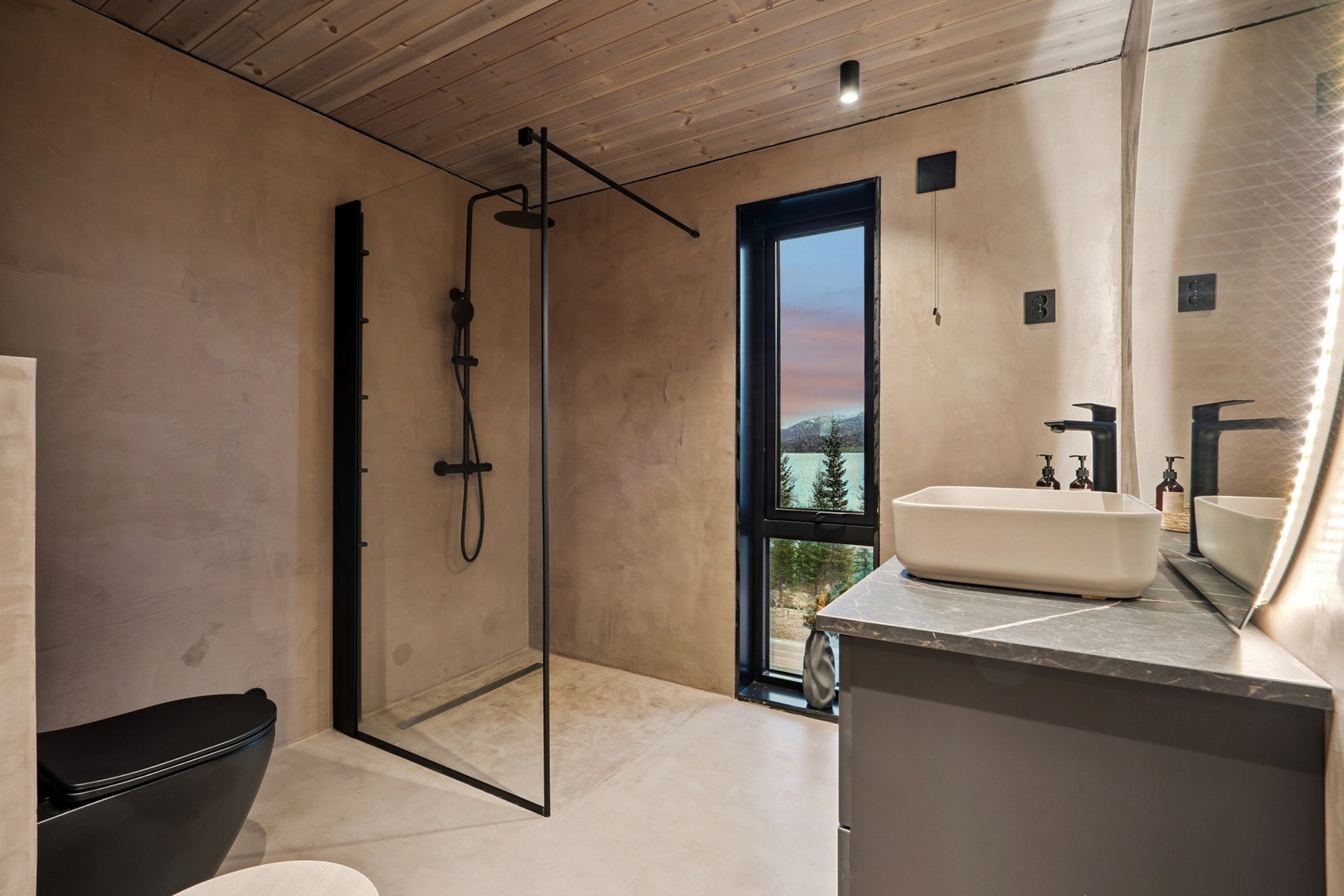 Lekkert bad med dusjhjørne, vegghengt toalett og store vinduer som slipper inn lys og natur. Galleribilde