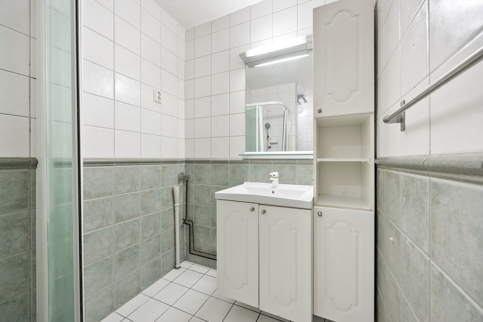 Flislagt baderom med servantinnredning, speilskap og dusjkabinett. Galleribilde