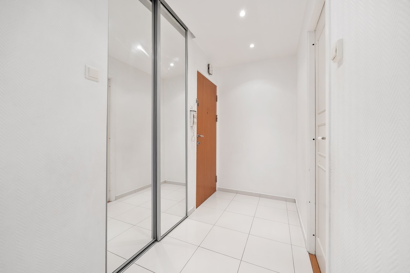 Entré med flislagt gulv og en romslig skyvedørsgarderobe med speilfronter for oppbevaring. Galleribilde