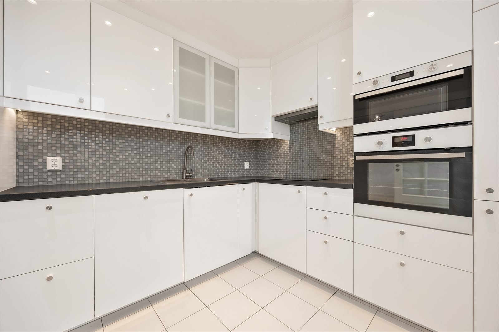 Benkeplate i laminat med nedfelt kum i rustfritt stål og mosaikkfliser over benken. Galleribilde