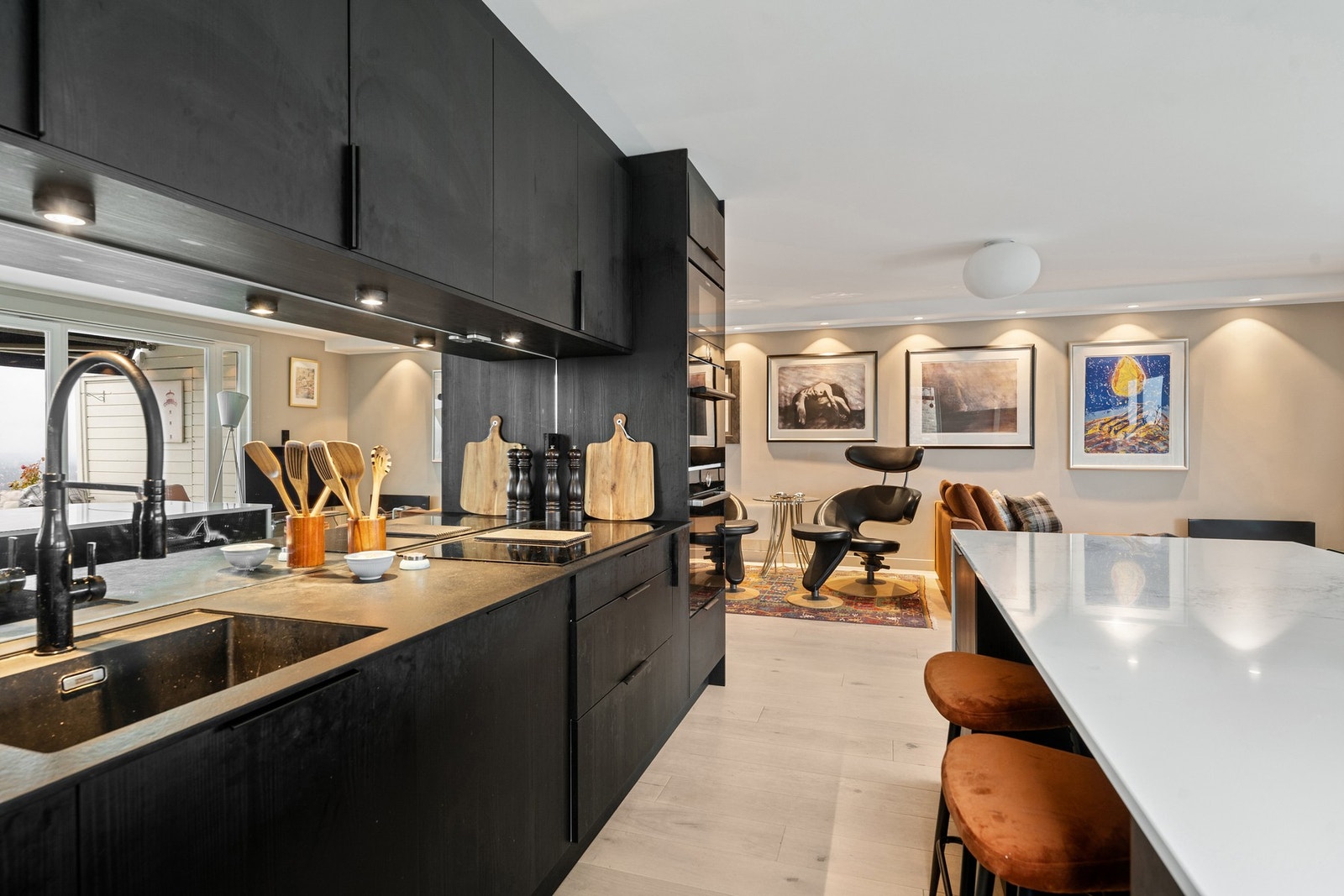 Stilrent kjøkken med moderne armatur og speilfelt mellom benk og overskap som gir rommet ekstra dybde og lys. Galleribilde