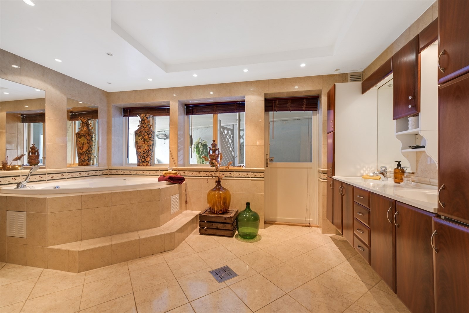 Stor bad med flis på gulv og vegger, og malt tak med spotter. Dør ut til overbygget uteplass. Galleribilde