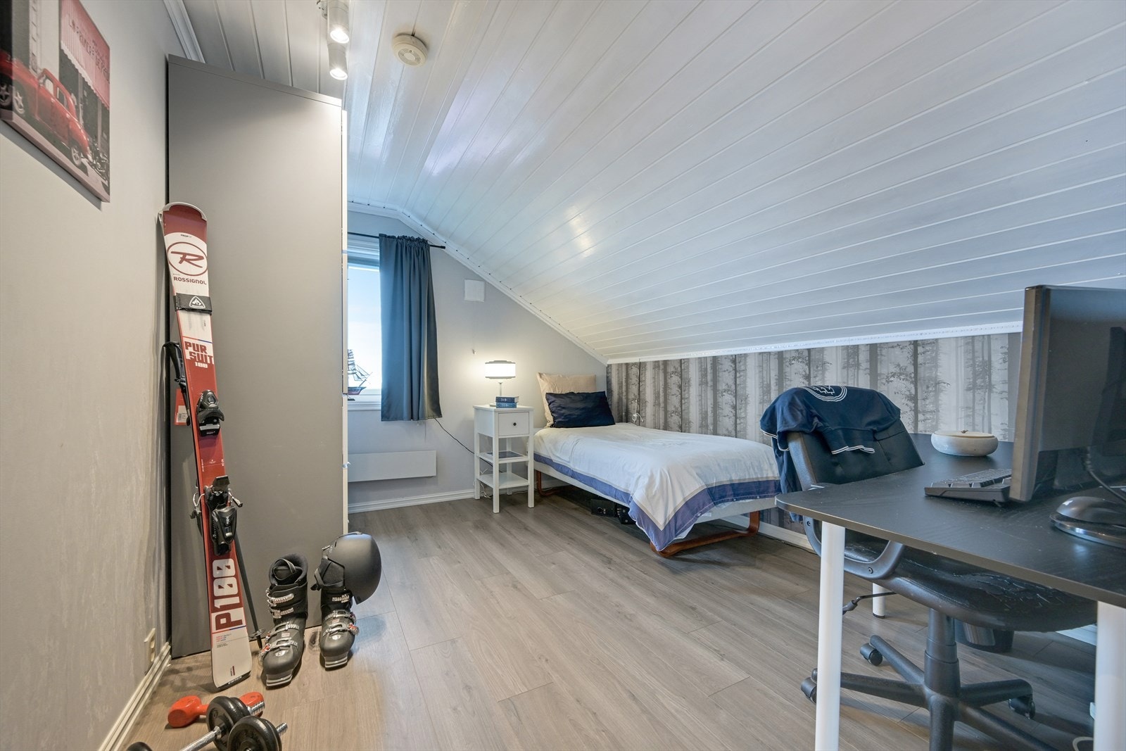 Soverom med laminat på gulv, tapet på veggene og malt panel i taket. Garderobeskap. Galleribilde