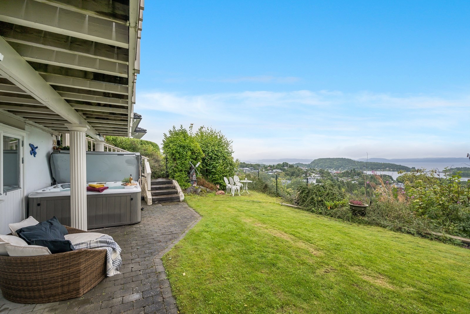 Hage med gressplen, enkelte prydbusker, stauder og naturlig vegetasjon. Galleribilde