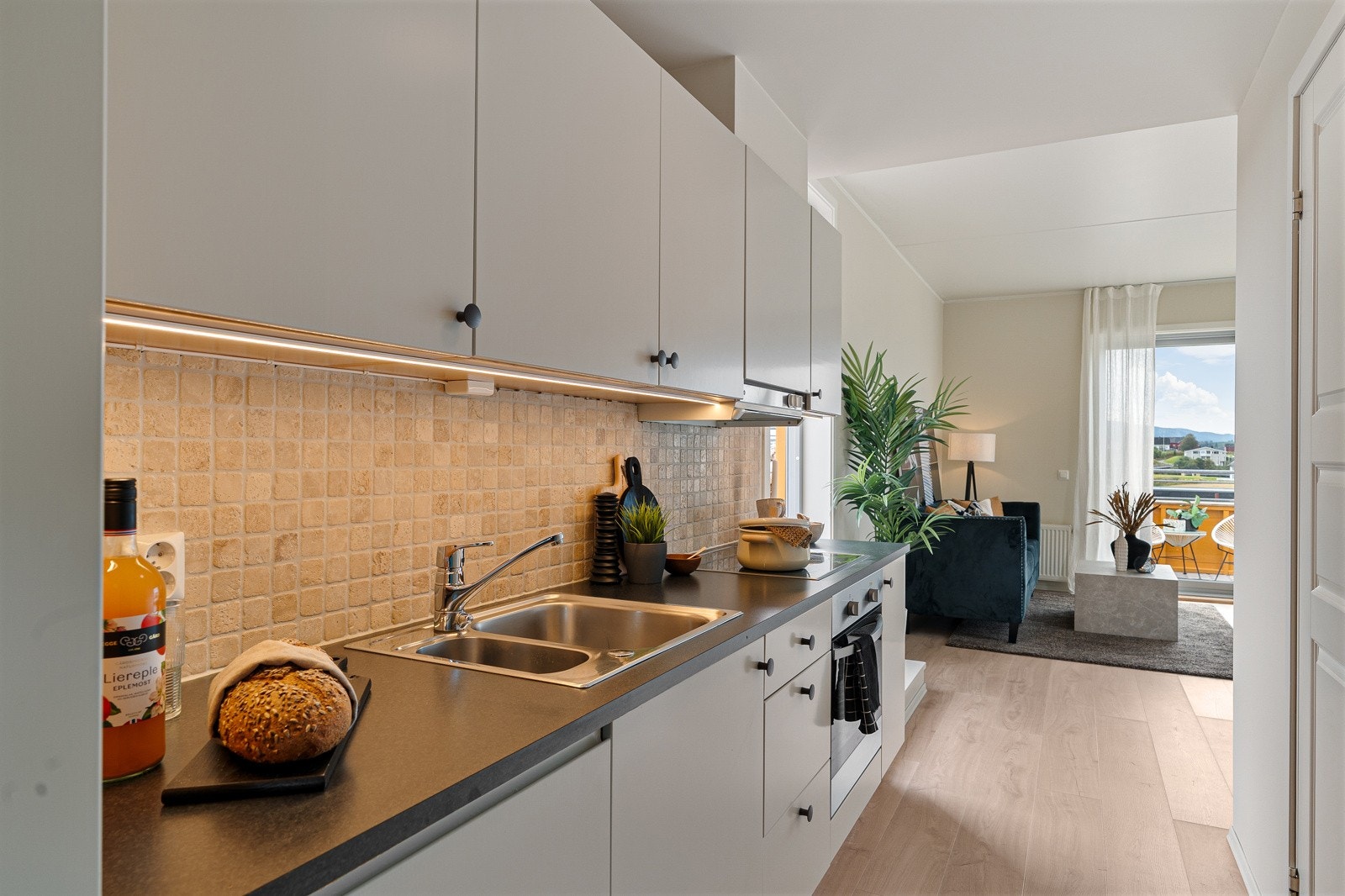 Kjøkkenet er godt utnyttet med over- og underskap, noe som gir rikelig oppbevaring og et helhetlig uttrykk. Galleribilde