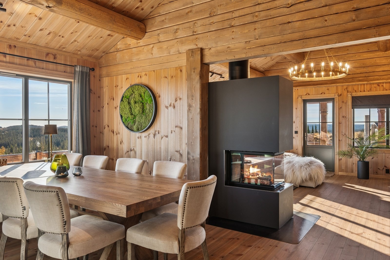 En peis med innsats fungerer som en elegant romdeler mellom stue og spisestue. Med glass på tre sider kan du se flammebildet fra flere vinkler i rommet, og i dette tilfellet fra flere rom i hytta. Galleribilde