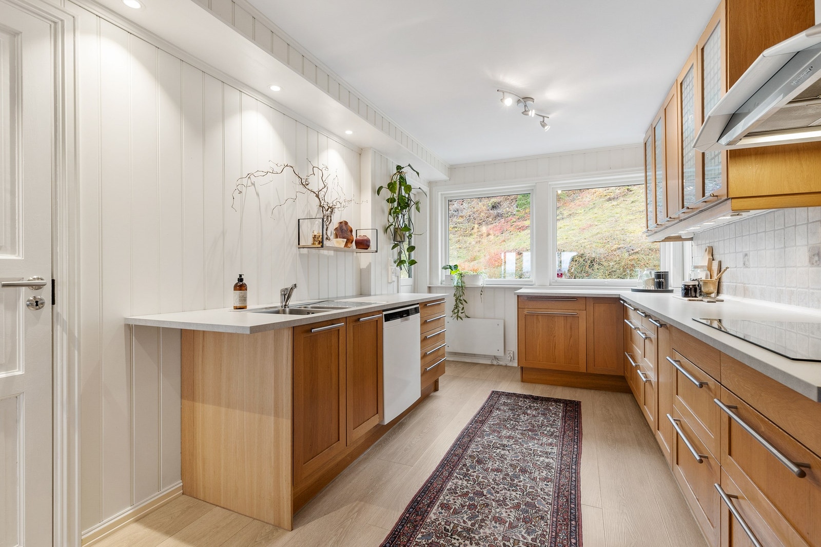 Åpen kjøkkenløsning. Innredningen er fra ukjent årstall med profilerte fronter. Benkeplate av laminat. Nedfelt oppvaskkum med ett-greps kjøkkenarmatur. Galleribilde