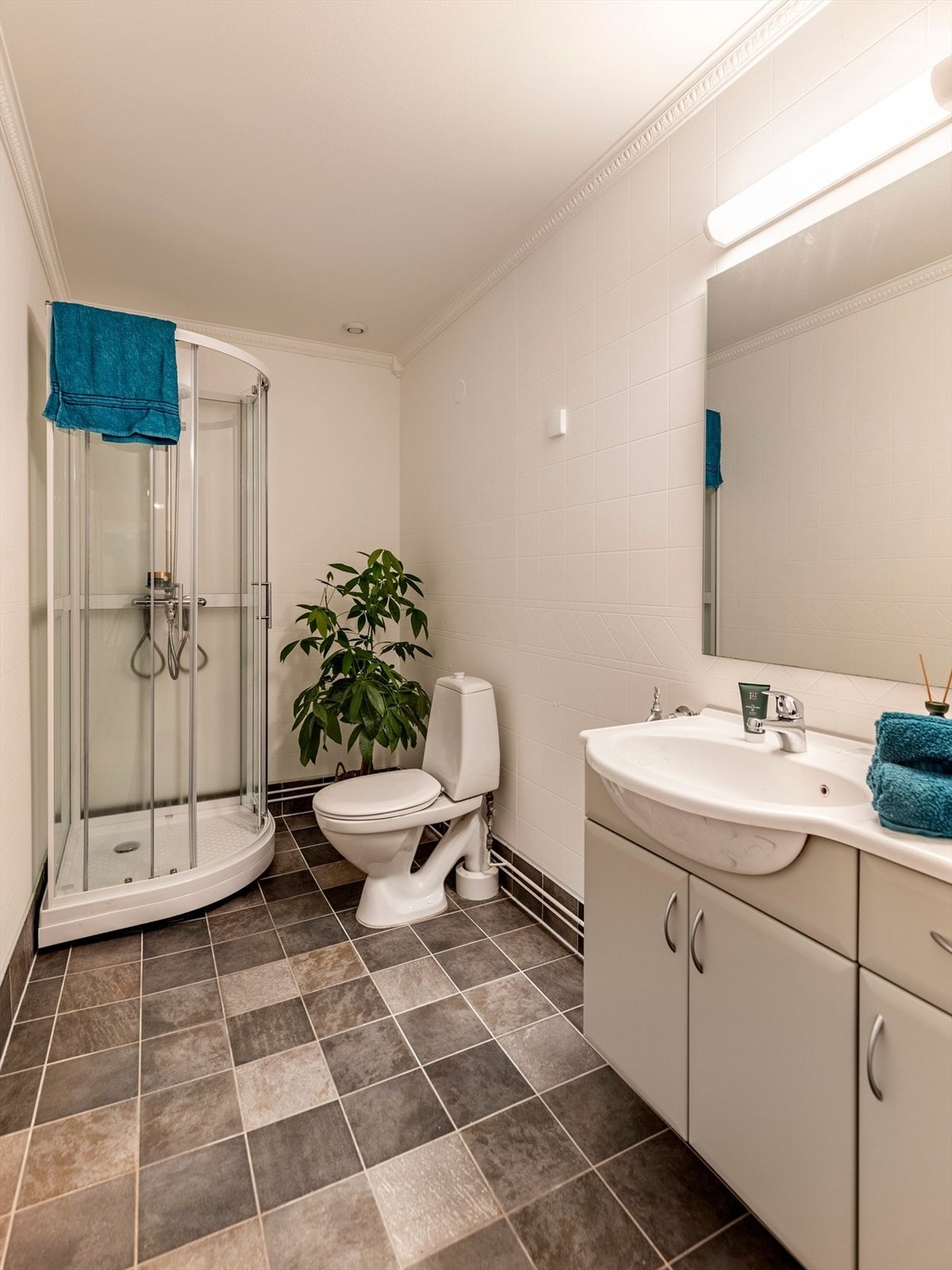 Badet er innredet med hvitmalte veggfliser som avsluttes mot taket med stukkatur. Gulvet har fliser i jordtoner og er utstyrt med gulvvarme. Galleribilde