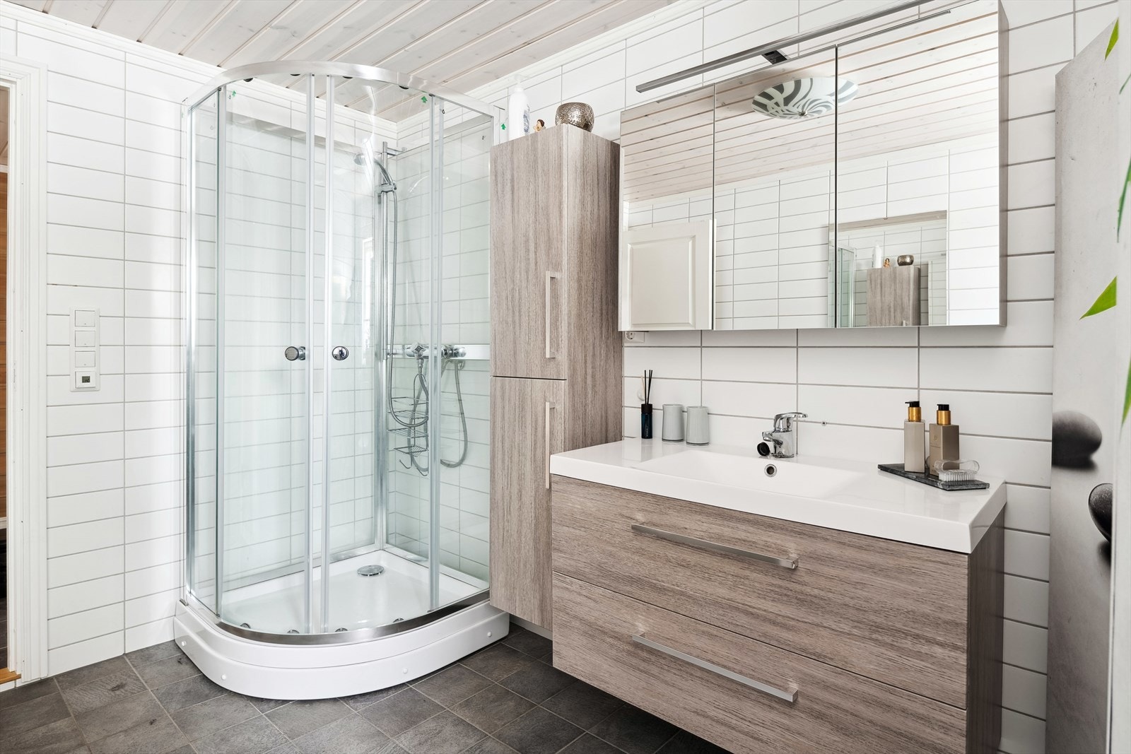 Badet er innredet med toalett, servant på innredning og dusjkabinett. Galleribilde