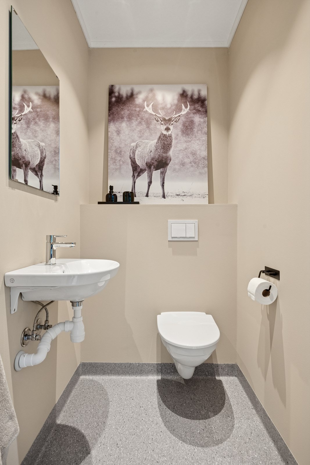 Toalettrommet i boligen er praktisk og funksjonelt. Gulvet har vinylbelegg, mens veggene er malt. Rommet er utstyrt med servant og vegghengt toalett. Galleribilde