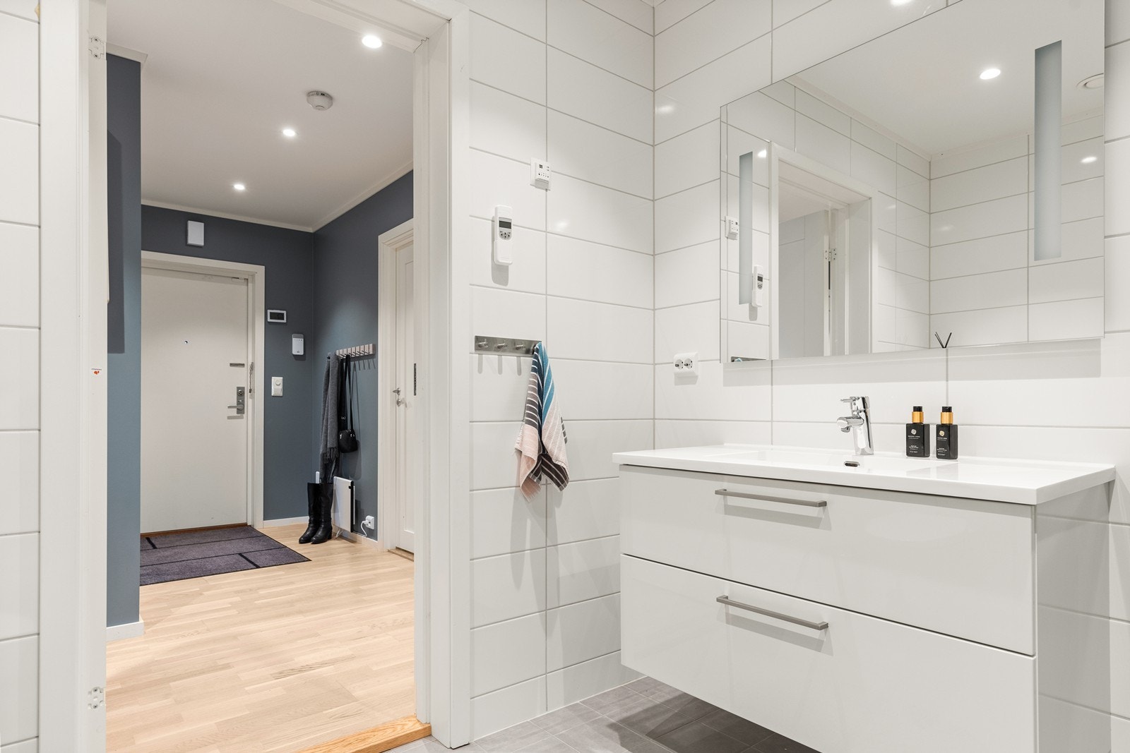 Baderomsinnredningen har et stilrent uttrykk, med heldekkende servant, og speil med led-lys over servanten Galleribilde