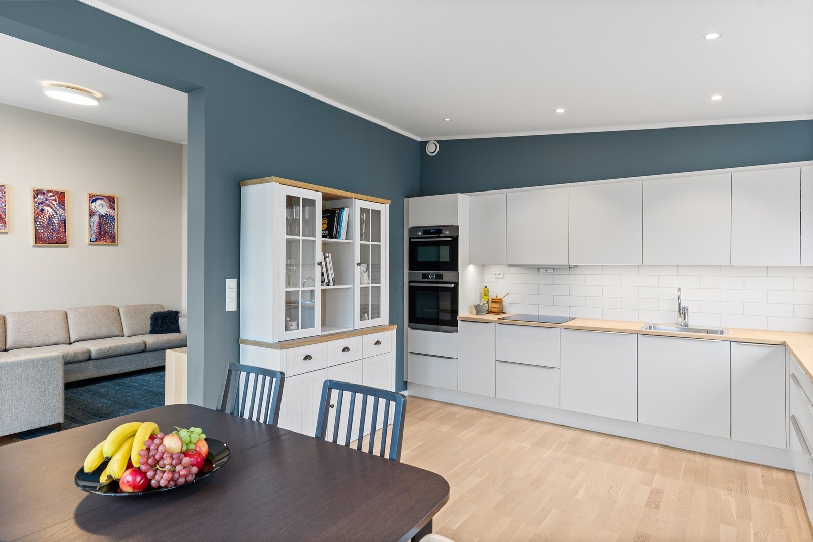 Romslig kjøkken, hvor den mørkere fargen som på kontrastveggen i stua, gjentas, for en gjennomført stil. På kjøkkenet er det en tidsriktig innredning fra HTH, med slette fronter og heltre benkeplate med nedfelt oppvaskkum. Det er integrerte hvitevarer Galleribilde