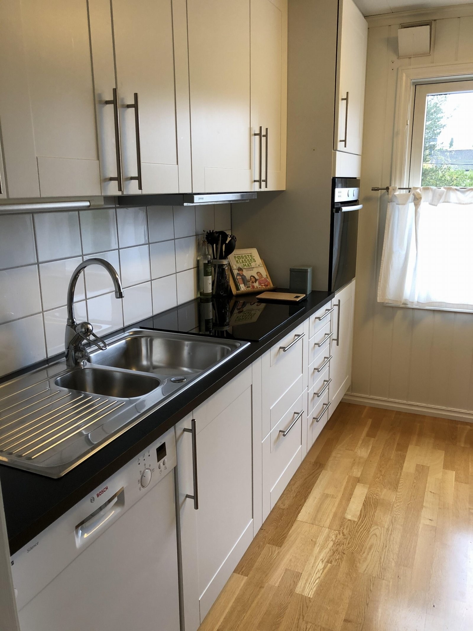 Pen kjøkkeninnredning med speilfronter samt laminert benkeplate og flis mellom over- og underskap. Dette bildet er tatt for 6 år siden og noen avvik vil forekomme. Galleribilde