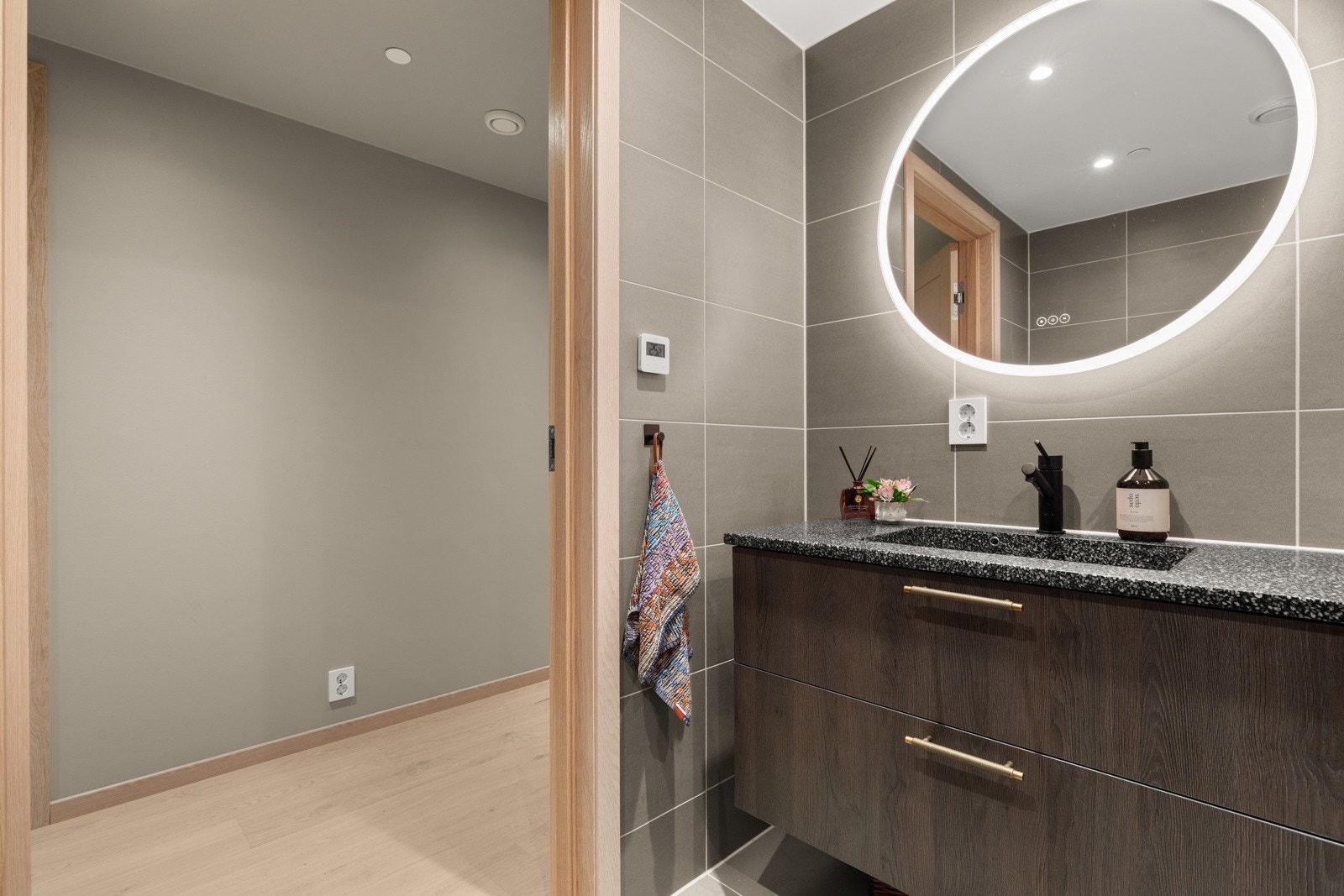 Innredningen består av vegghengt toalett, dusjhjørne med glassvegger, servant med underskap og speil. Det er opplegg for vaskemaskin på badet. Galleribilde