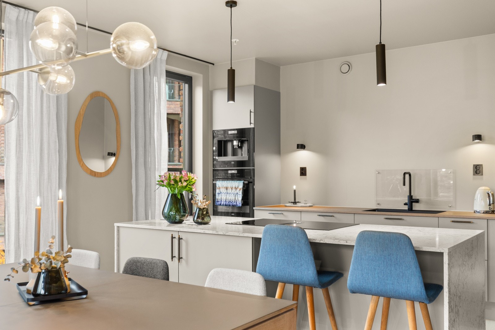 Kjøkkenet er stilrent, moderne og innbydende. Her får du en flott HTH-innredning fra 2024 medbenkeplater av stein og laminat, samt slette skapfronter og plateslått backsplash som gir et tidløst og elegant preg. Galleribilde